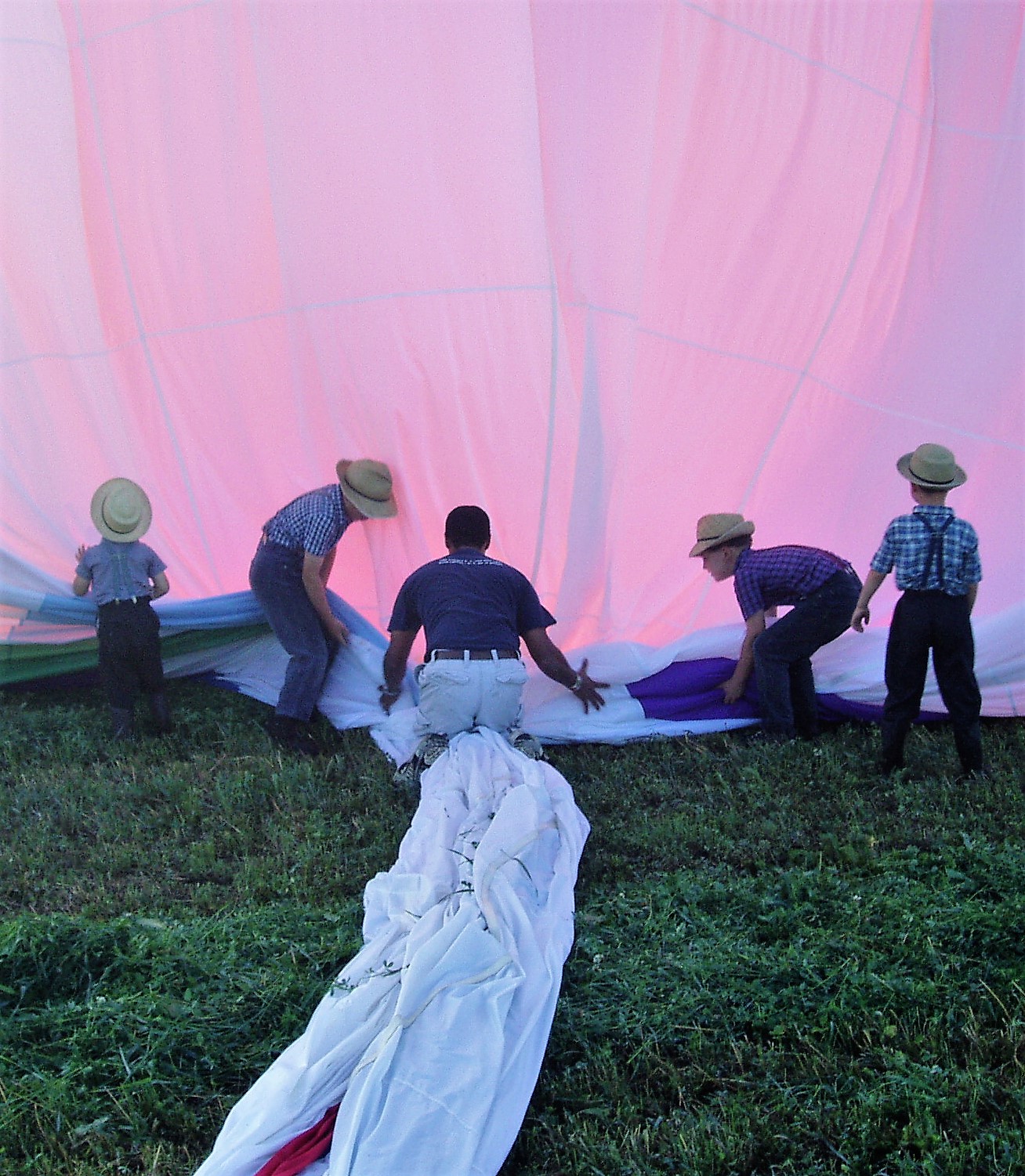 Passengers enjoying a colorful hot air balloon canopy from below
