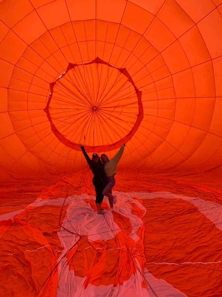 Hot air balloon floating above patchwork fields at golden hour