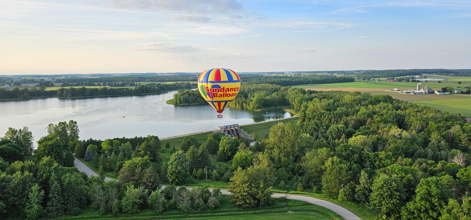 Hot air balloon gliding over winding Ontario river at sunset