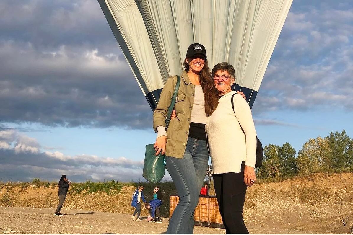Wide view of colourful balloons floating above patchwork farmland