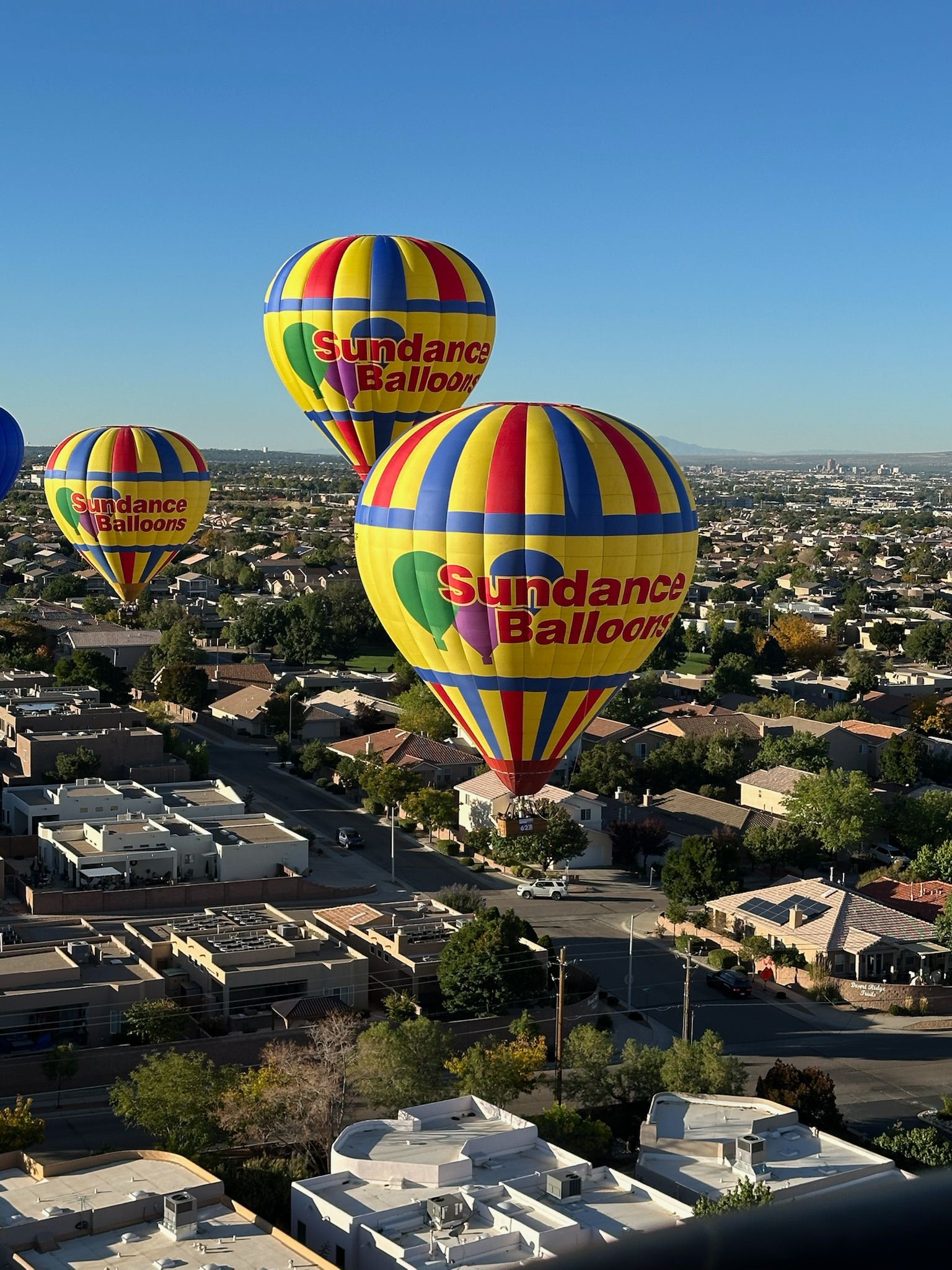 Sundance hot air balloon floating above homes and countryside at sunrise